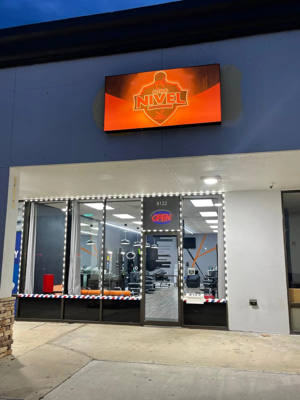 Fachada iluminada de Otro Nivel Barber Shop, local 8122