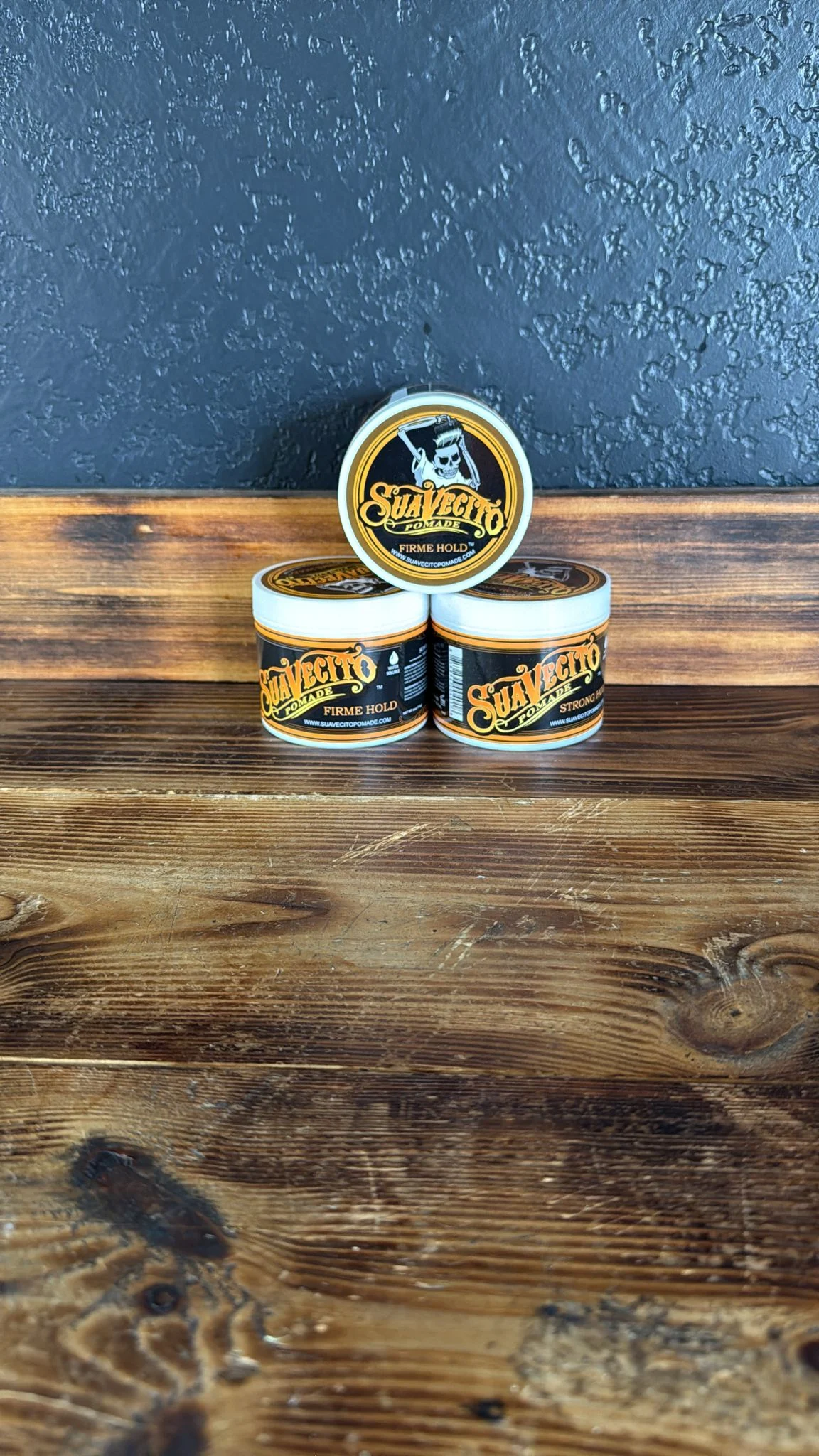 Tres envases de Suavecito Pomade sobre el mostrador de la barbería